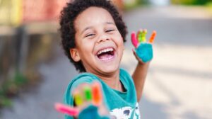 A child smiling while showing his colorful hands