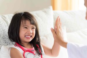 A child gives high five to a doctor after her sick visit